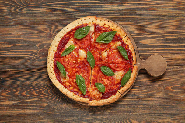 Board with tasty pizza on wooden background - Photo, Image