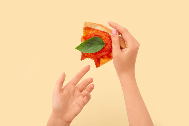 Woman holding slice of bitten pizza on yellow background - Photo, Image