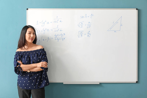 Profesor de matemáticas asiático cerca de flipboard en el aula - Foto, Imagen