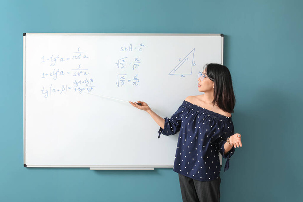 Asian Math teacher near flipboard in classroom - Photo, Image
