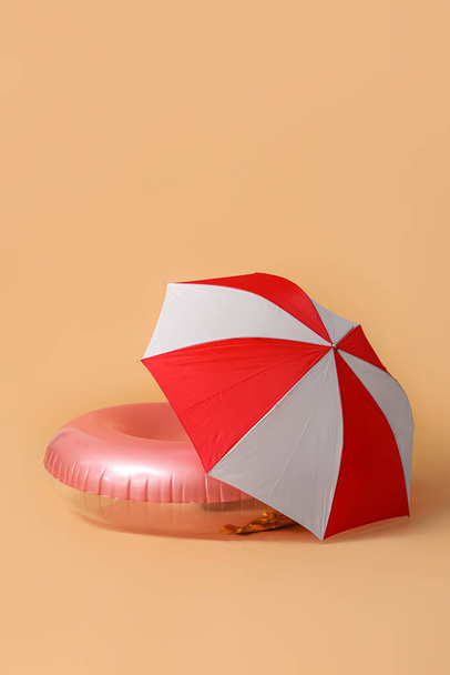 Плавание кольцо с пляжным зонтиком на бежевом фоне - Фото, изображение