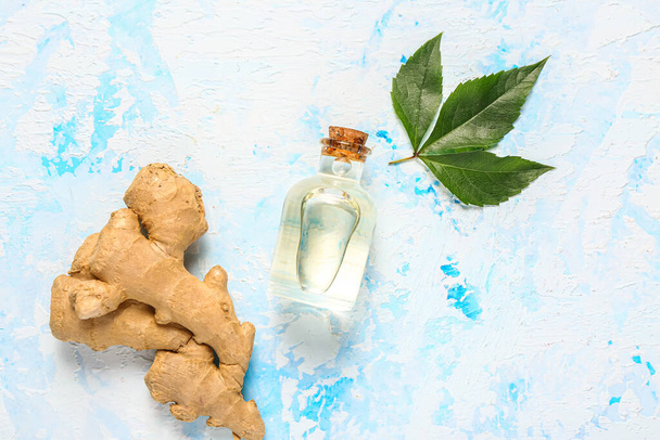 Butelka imbirowego oleju kosmetycznego i liście na jasnoniebieskim tle - Zdjęcie, obraz