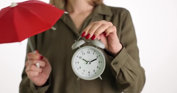 La mujer sostiene el despertador y el paraguas rojo. Protección y seguridad del tiempo personal - Imágenes, Vídeo