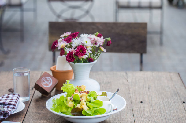 Insalata fatta in casa cibo sano con vaso di fiori sul tavolo di legno - Foto, immagini