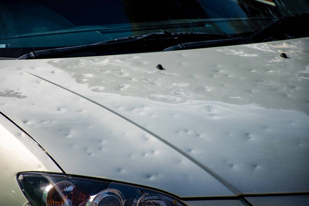 Car hood damaged by major hailstorm hailstones. Car insurance repair dents. Dented car bonnet car after storm weather - Photo, Image