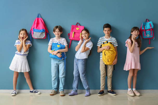 Petits élèves avec sacs à dos près du mur bleu - Photo, image