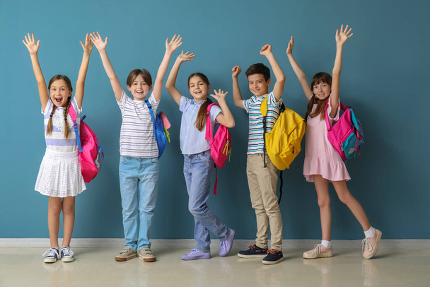 Kleine leerlingen met rugzakken bij de blauwe muur - Foto, afbeelding