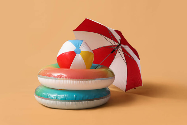 Swim rings with beach ball and umbrella on beige background - Photo, image