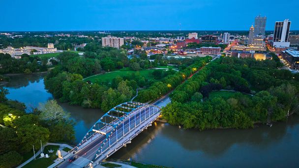 Изображение Воздушного моста Мартина Лютера Кинга в центре Форт-Уэйна с парком и зданиями в сумерках - Фото, изображение