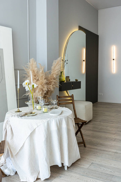 romantic table is served for two in the kitchen in a bright open-plan apartment in a modern style with light walls and wooden floors. - Foto, immagini