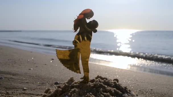 Пластиковая фигурка молодого человека в влюбленную девушку и парня, обнимающего в песке на пляже морского побережья в солнечный летний день крупным планом. Символ концепции знак любви радость падения влюбленных влюбленность возлюбленная - Кадры, видео