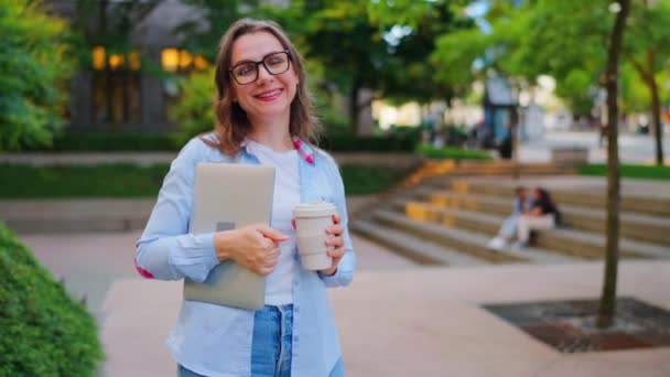 Портрет женщины, стоящей на улице с ноутбуком и кофе в руках после рабочего дня в офисе. Медленное движение - Кадры, видео