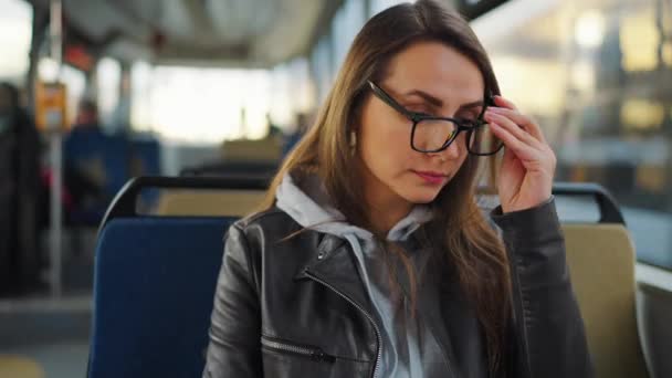 Toplu taşıma. Tramvaydaki gözlüklü kadın akıllı telefon konuşmaları yapıyor ve arkadaşlarıyla mesajlaşıyor. Şehir, şehir, ulaşım. - Video, Çekim