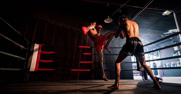 Asian and Caucasian Muay Thai boxer unleash knee attack in fierce boxing training session, delivering knee strike to sparring trainer, showcasing Muay Thai boxing technique and skill. Spur - Photo, Image