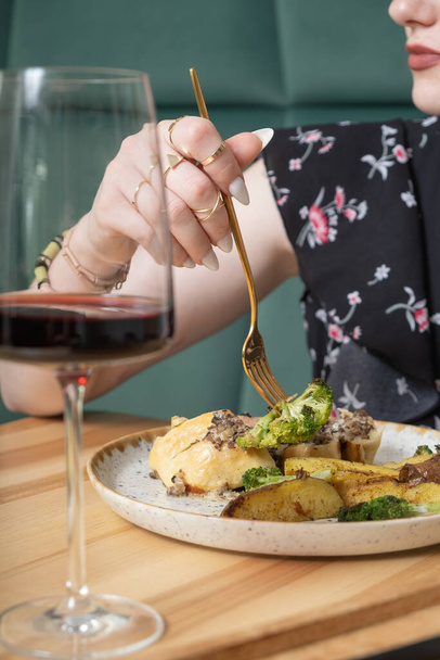 Primo piano di una forchetta nella mano di una donna su un piatto con cibo delizioso in un ristorante. - Foto, immagini
