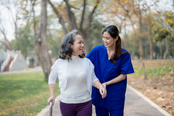 Cuidados com os pacientes, cuidados femininos, jovens mulheres asiáticas estão cuidando dos idosos, fornecendo muletas e caminhando para os pacientes, e exercitando suas pernas e joelhos nos parques do parque. - Foto, Imagem