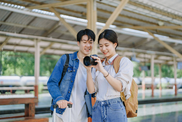 Молодая пара путешествует с помощью камеры, чтобы запечатлеть воспоминания во время ожидания поезда на station.travel концепции - Фото, изображение