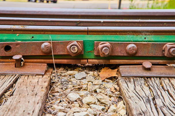 Зображення крупним планом з зеленого металу вздовж горіхів і болтів на залізничних коліях з листям і дерев'яними балками - Фото, зображення