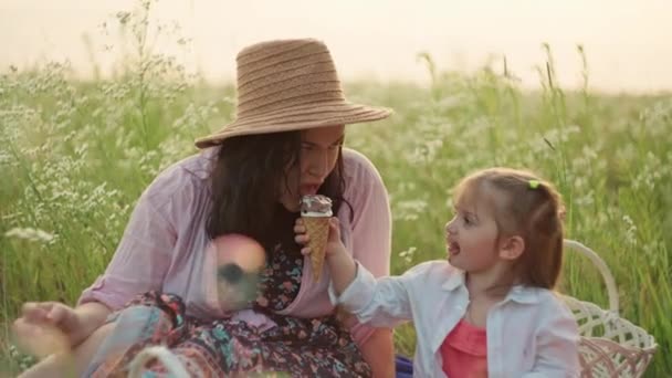 Μια ικανοποιημένη μητέρα και τα παιδιά της αφεθείτε στις απολαύσεις του παγωτού σε ένα καταπράσινο λιβάδι, απεικονίζοντας την ουσία μιας ευτυχισμένης παιδικής ηλικίας και αποπνέοντας γνήσια χαμόγελα της οικογένειας Bliss.  - Πλάνα, βίντεο