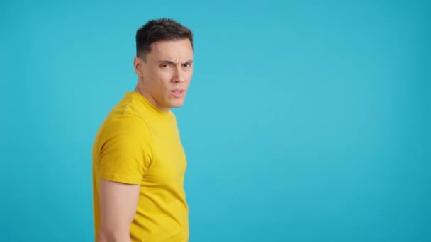 Video in studio with blue background of a man shakes head while walking from side to side - Footage, Video