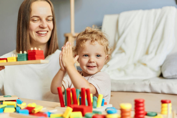 Cognitive development puzzles. Montessori learning approach. Fun family activities. teacher or mother playing with baby with logical toys at home interior - 写真・画像