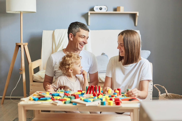 Interactive learning games. Playful outdoor adventures. Parent-child bonding time. Imaginative storytelling fun. Mother father and her child girl playing with colorful logical sorter toy. - Foto, Imagen