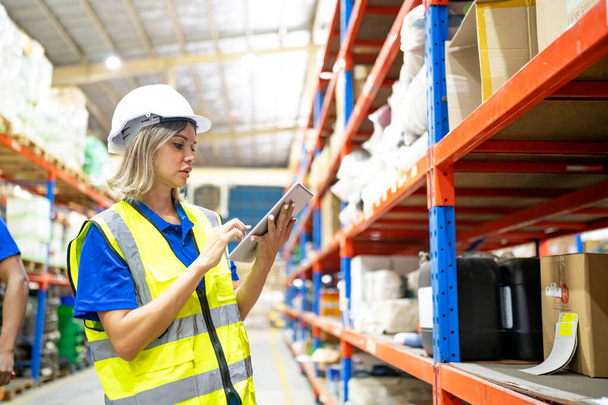 Warehouse worker checking the inventory. Products on inventory shelves storage. Worker Doing Inventory in Warehouse. Dispatcher in uniform making inventory in storehouse. supply chain concept - Photo, Image