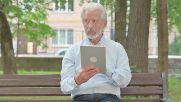 Senior oude man met behulp van Tablet tijdens het zitten in het park - Video