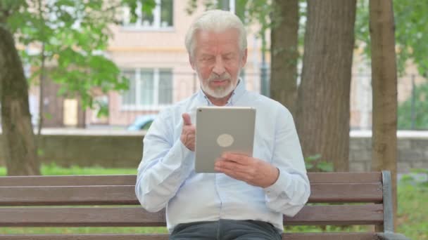 Senior oude man doet video Chat op Tablet tijdens het zitten in het park - Video