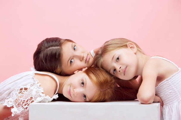 Portrait of little beautiful children, girls posing together against pink studio background. Well-being. Concept of skincare, childhood, cosmetology and health, beauty, organic products, ad - Valokuva, kuva
