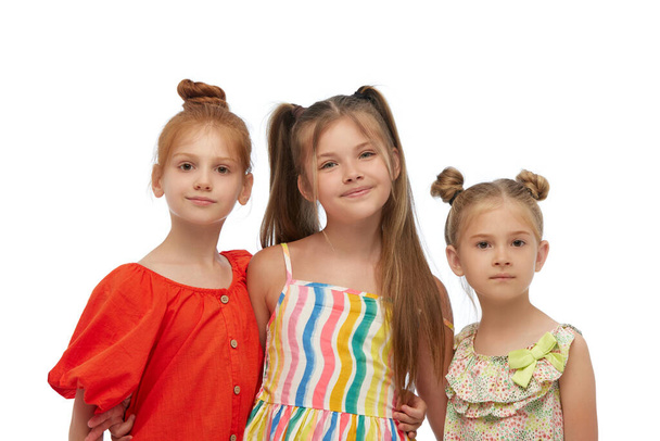 Beautiful little girls, children in colorful dresses posing, looking at camera against white studio background. Concept of childhood, fashion, family, emotions, lifestyle, care, ad - Foto, Bild