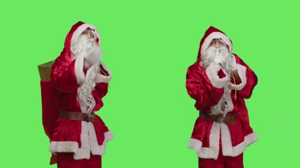 Батько Різдво показує німий символ, висловлюючи приватність і тишу над зеленим кольором в студії. Санта-Клаус з подарунковою сумкою робить знак хіта, щоб тримати в таємниці, приватний сезонний зимовий характер. - Кадри, відео