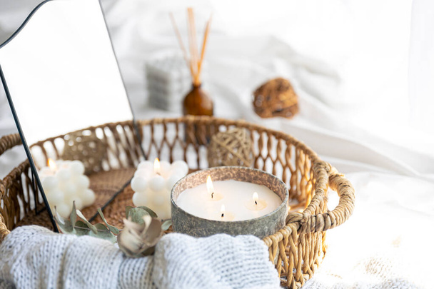 Спа-композиция со свечами, зеркалом и ароматом палками в плетеной корзине на кровати. - Фото, изображение