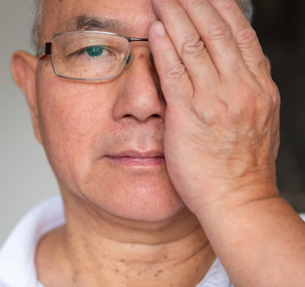 Un hombre probando la visión en su ojo derecho usando un par de gafas varifocales. - Foto, Imagen