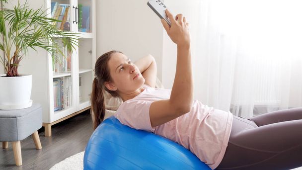 Νεαρή γυναίκα influencer καταγραφή βίντεο στο smartphone, ενώ κάνει ασκήσεις φυσικής κατάστασης. - Φωτογραφία, εικόνα