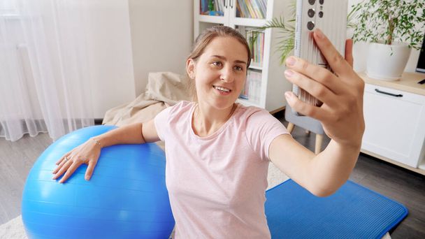 Retrato de jovem blogueira esportiva filmando vídeo para mídias sociais de seu treinamento de fitness em casa. Esportes, fitness e ioga blogueiros e influenciadores. - Foto, Imagem