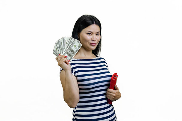 Młoda Azjatka pokazuje fankę dolarów i trzyma czerwony portfel. Odizolowane na biało. - Zdjęcie, obraz