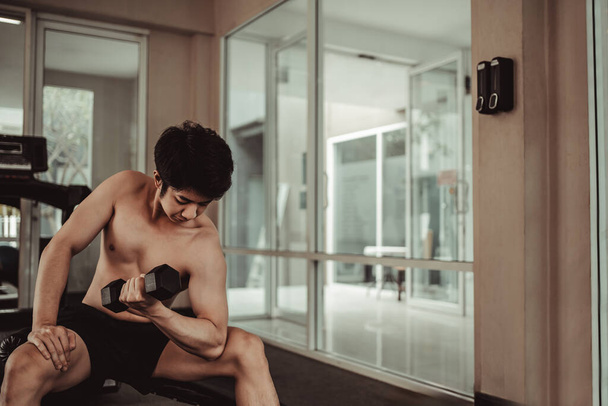 Muscular Young Man Trening z hantlami w siłowni - Koncepcja treningu siłowego i fitness, Aktywny trening siłowy, fitness i determinacja. - Zdjęcie, obraz