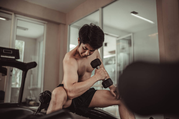 体力トレーニングとフィットネスコンセプト,アクティブジムワークアウト,フィットネスと決断でダンベルと運動する筋肉の若い男. - 写真・画像