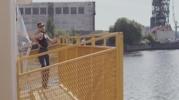 Pełen strzał ekscentrycznej kaukaskiej pary w klasycznych strojach tańczącej modnie na metalowo żółtej konstrukcji na nabrzeżu - Materiał filmowy, wideo