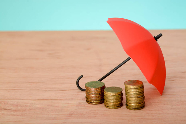 Červený deštník a mince s kopií prostoru. Koncepce ochrany peněz a zajištění bezpečnosti - Fotografie, Obrázek