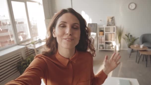 POV handheld slowmo της νεαρής μελαχρινής γυναίκας μιλώντας στην κάμερα, ενώ κινηματογράφηση βίντεο blog για την εργασία της στο γραφείο - Πλάνα, βίντεο