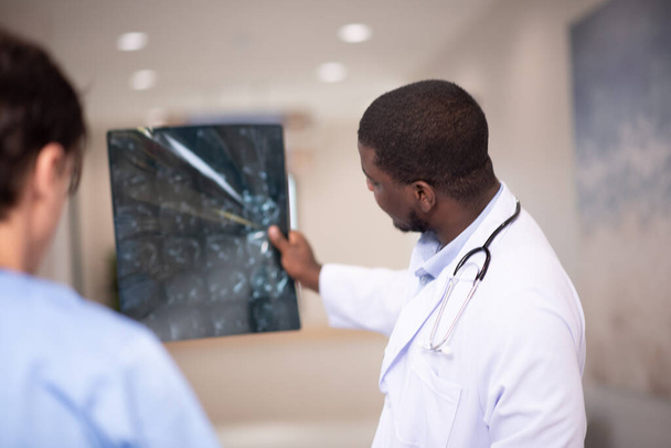 Artsen onderzoeken x-ray in gang van het ziekenhuis - Foto, afbeelding