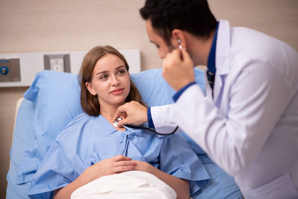 Controllo medico su paziente donna sdraiata in letto d'ospedale - Foto, immagini
