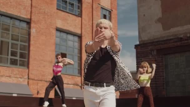 Μοντέρνα ομάδα voguers σε ρετρό ρούχα χορό στην κάμερα κατά παλιά κτίρια κόκκινο τούβλο σε εξωτερικούς χώρους το καλοκαίρι - Πλάνα, βίντεο