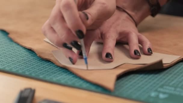 Primer plano plano de las manos de la artesana rastros de plantilla en pieza de cuero para cortar - Metraje, vídeo