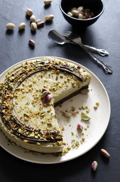 Delicious pistachio cheesecake ready to be served, mousse cake with chopped pistachio on a gray background. Overhead view. - Photo, Image