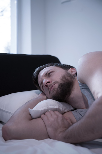 Awake man lying in bed - Фото, изображение