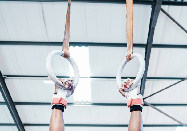 Hands, gymnastics ring and person in fitness for workout, strength training or competition. Closeup of hanging athlete, strong gymnast or acrobat holding on balance circles for performance exercise. - Photo, Image