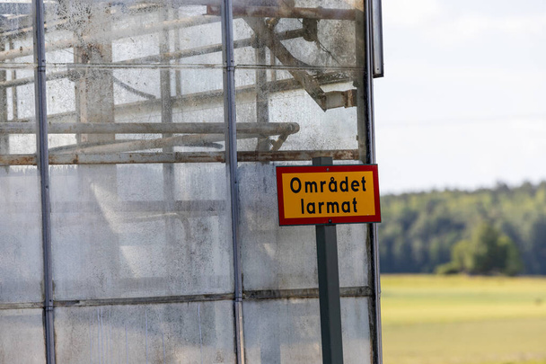 Sodertalje, Szwecja Żółta strona ostrzegawcza po stronie budynku na wsi mówi po szwedzku "Obszar jest zaniepokojony". - Zdjęcie, obraz